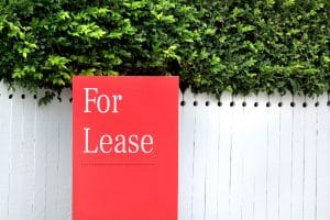 Red For Lease sign on a house in the rental property market