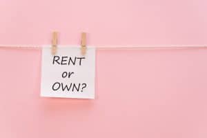 sticker with the inscription RENT or OWN hangs with a clothespin on a rope on a pink background